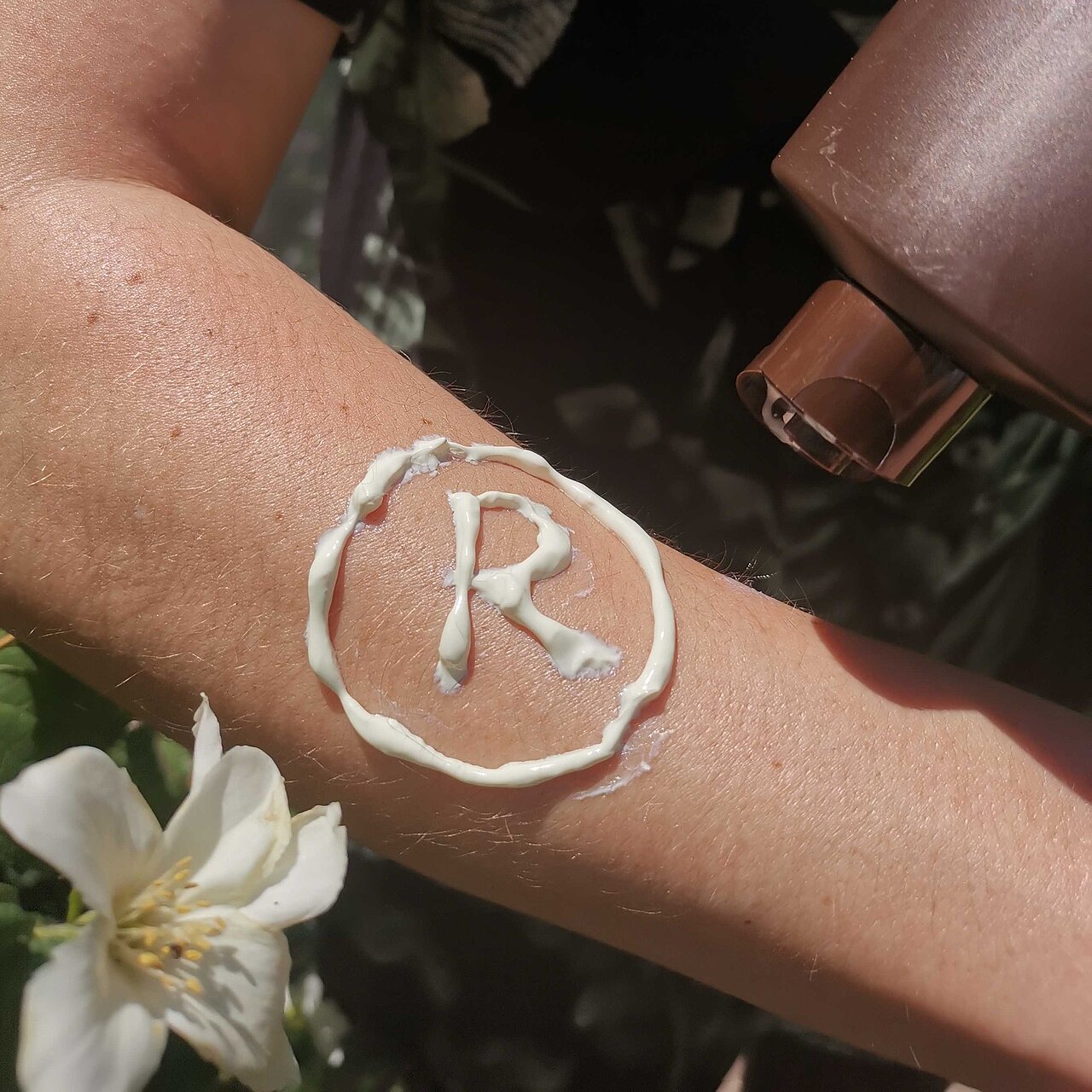 Registered-Symbol mit Sonnencreme auf Arm gezeichnet