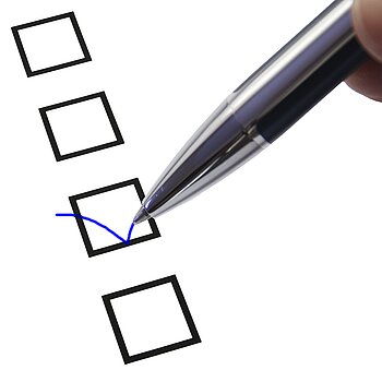 Ein Auswahlkästchen - wie auf einem Fragebogen - wird mit einem Kugelschreiber angehakt.