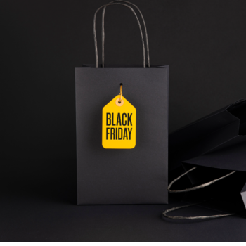 Schwarze Einkaufstasche mit einem Anhänger mit der Aufschrift Black Friday, vor schwarzem Hintergrund.