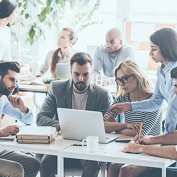 Menschen sitzen gemeinsam an einem Arbeitsplatz mit Computer