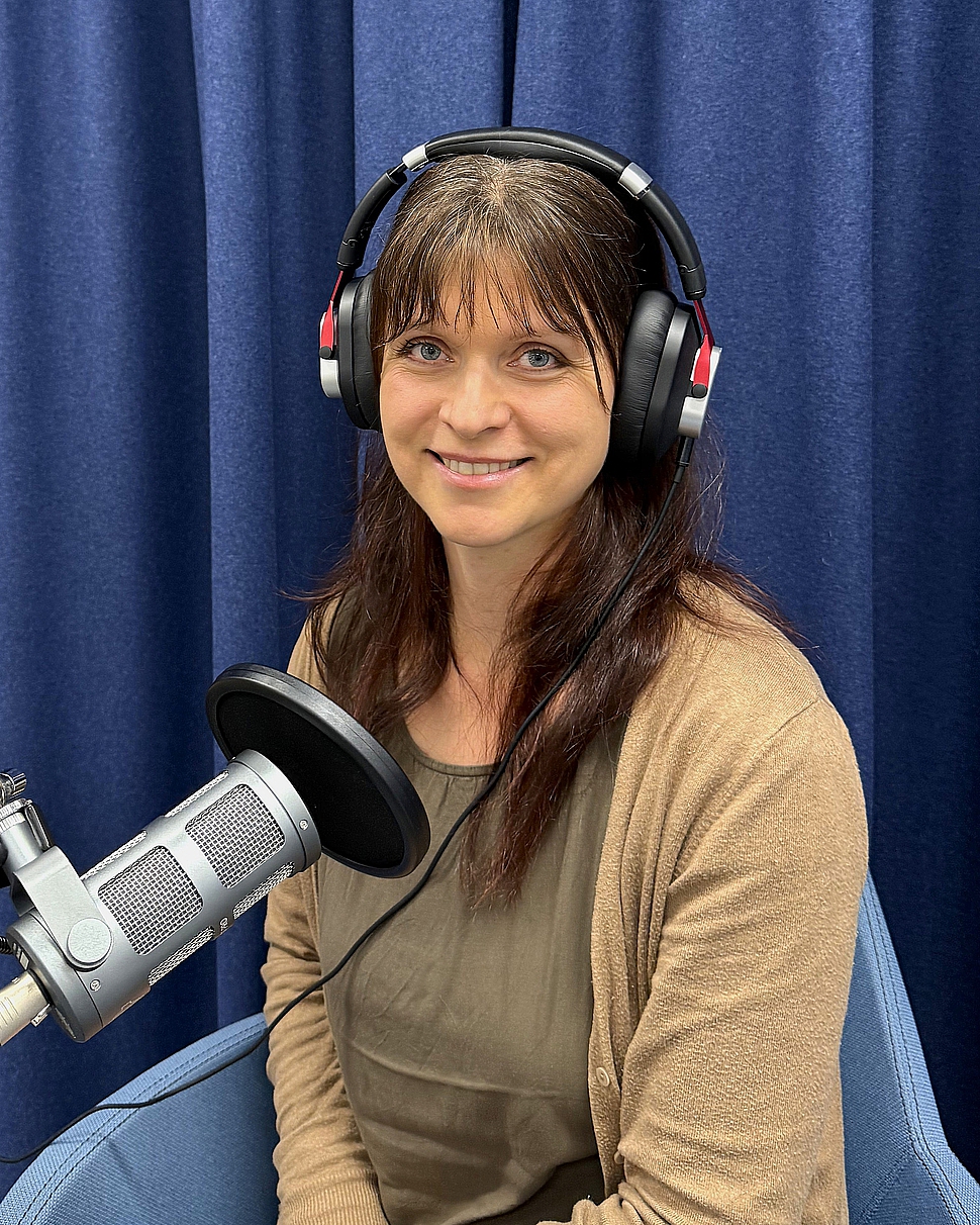 Foto von Podcast-Host Julia Zach mit Kopfhörer vor einem Podcast-Mikrofon