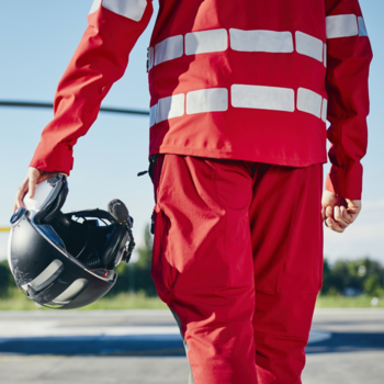 Rettungssanitäter von hinten zu sehen mit einem Helm in der linken Hand.