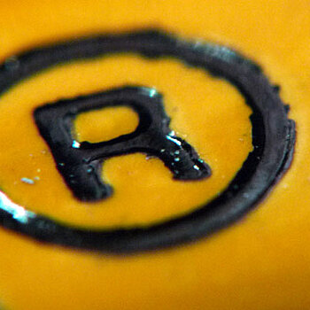 Zeichen für registrierte Marke (Buchstabe R in einem Kreis) auf gelbem Hintergrund