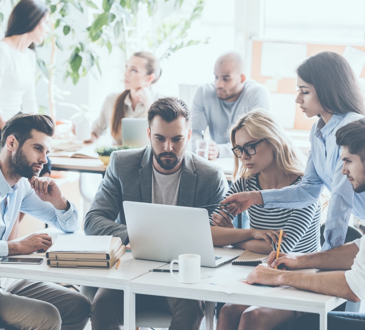 Menschen sitzen gemeinsam an einem Arbeitsplatz mit Computer