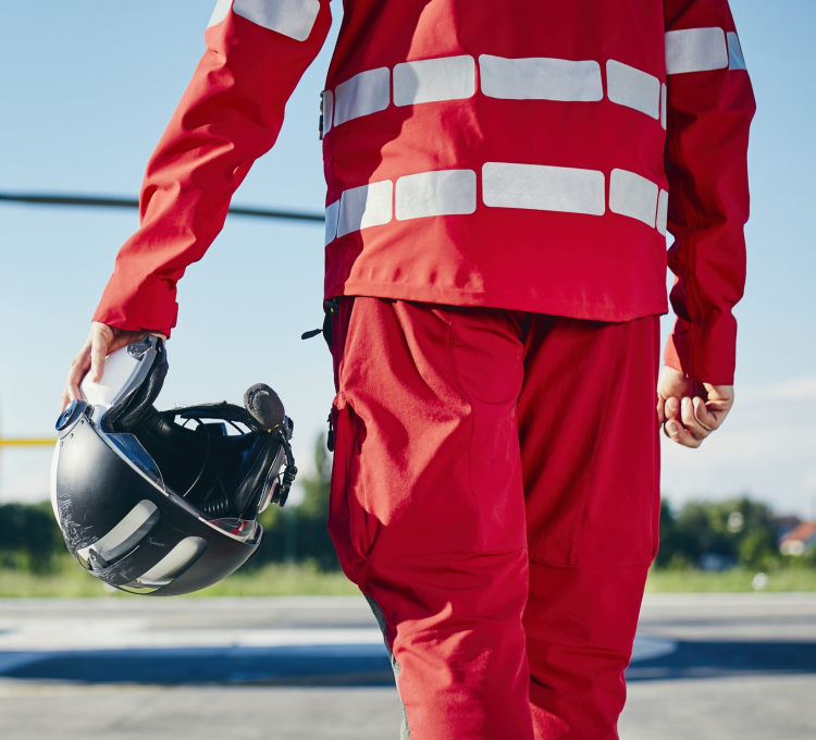 Rettungssanitäter von hinten zu sehen mit einem Helm in der linken Hand.