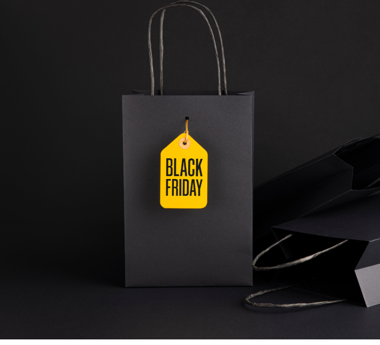 Schwarze Einkaufstasche mit einem Anhänger mit der Aufschrift Black Friday, vor schwarzem Hintergrund.